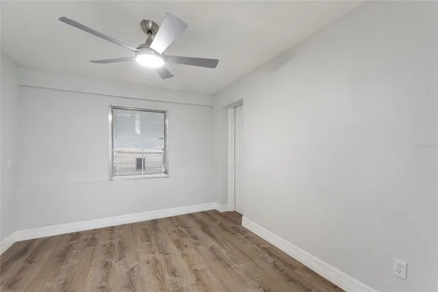 an empty room with wooden floor fan and windows