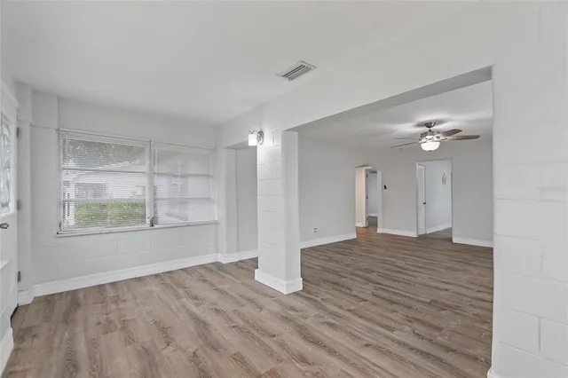 a view of empty room with wooden floor and fan
