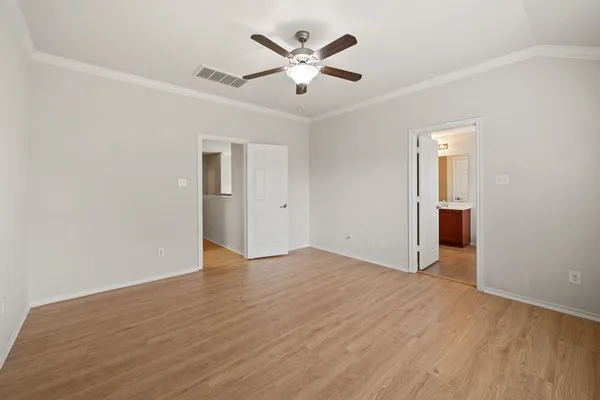 an empty room with wooden floor and ceiling fan