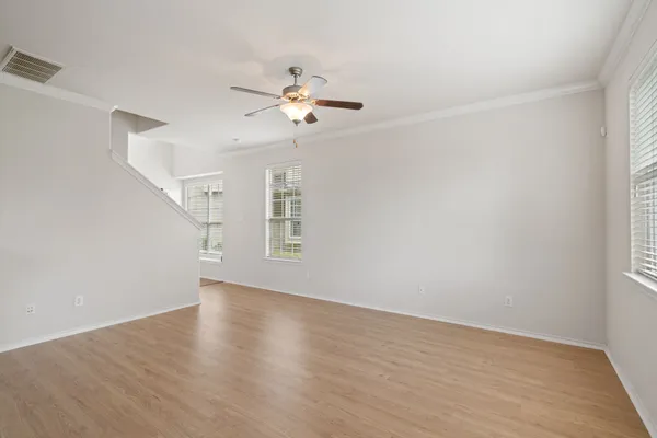 a view of an empty room with a window and wooden floor