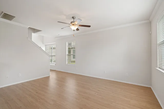 a view of an empty room with a window and wooden floor