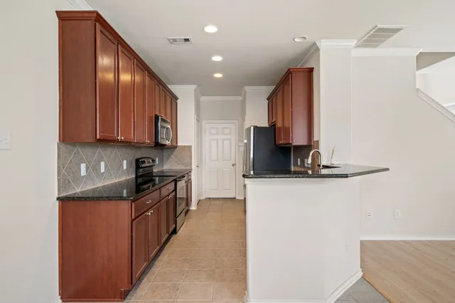 a kitchen with stainless steel appliances granite countertop wooden cabinets a stove top oven a sink and dishwasher