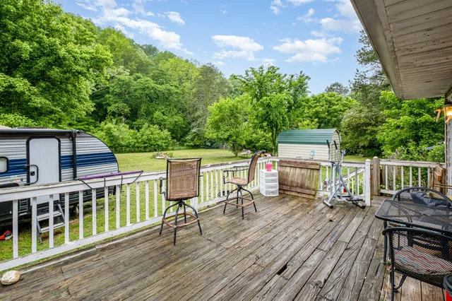 a view of a roof deck with table and chairs a barbeque with wooden floor and fence