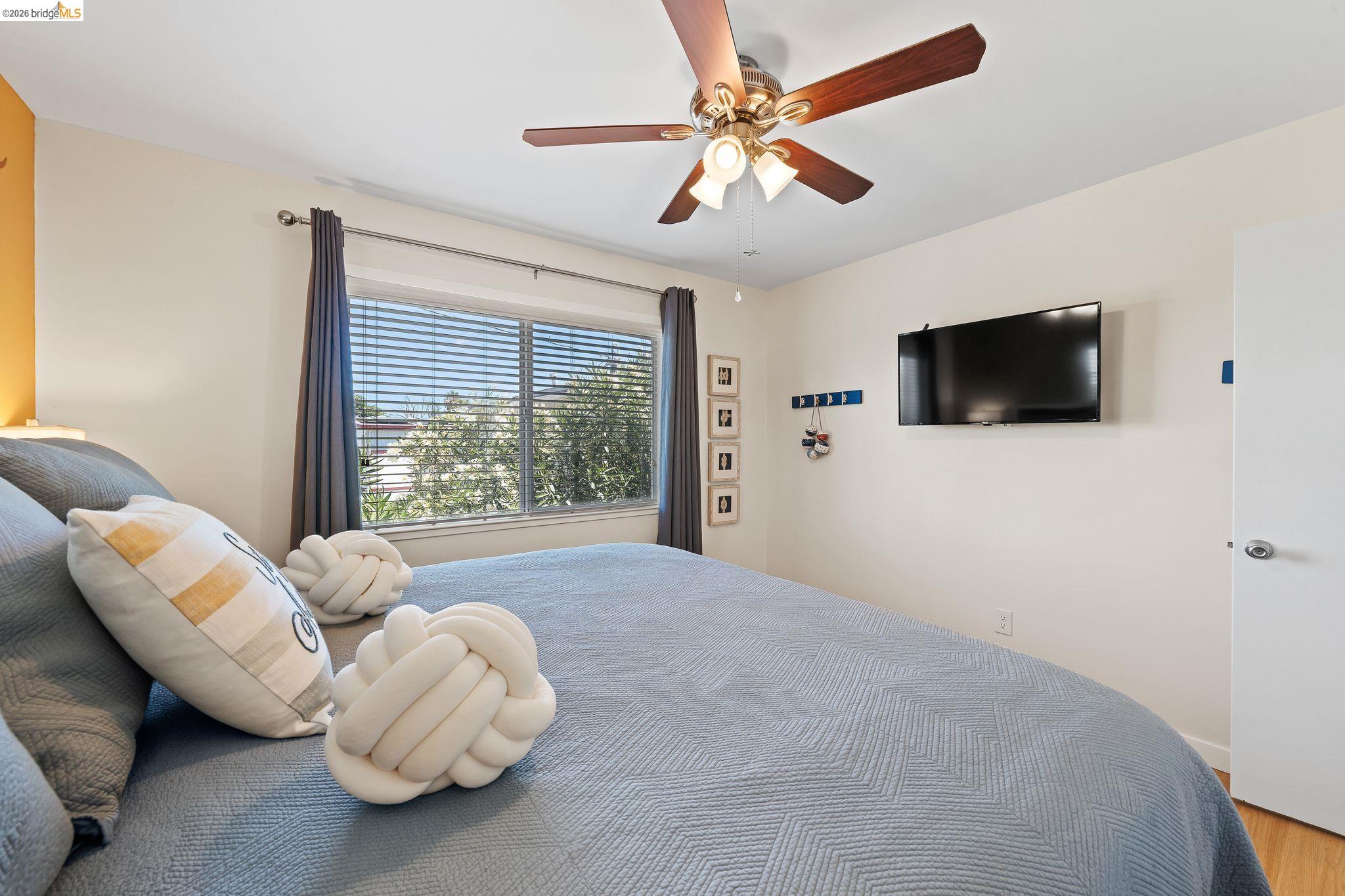 1704 Taylor Road Bethel Island, CA 94511 - Photo 37 of 73 Bedroom featuring a ceiling fan with light fixture, window with blinds and dark drapery, wall-mounted television, and wood-finish flooring