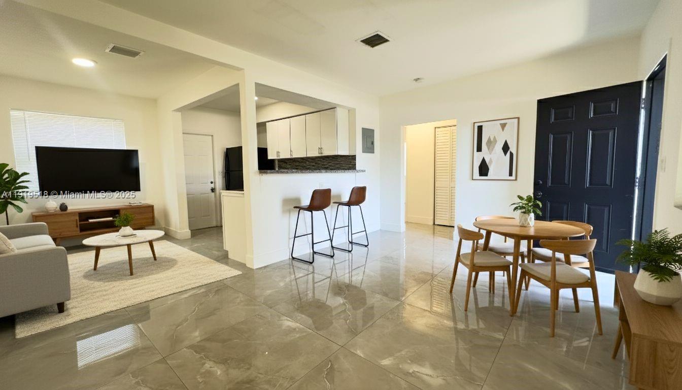 720 82nd Street, Unit 718 Miami Beach, FL 33141 - Photo 1 of 12 a living room with furniture a flat screen tv and kitchen view