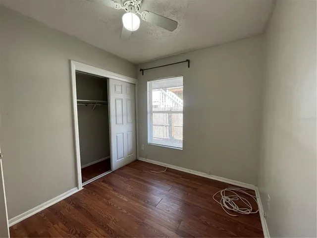 an empty room with wooden floor cabinet and windows