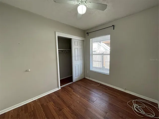 an empty room with wooden floor cabinet and windows