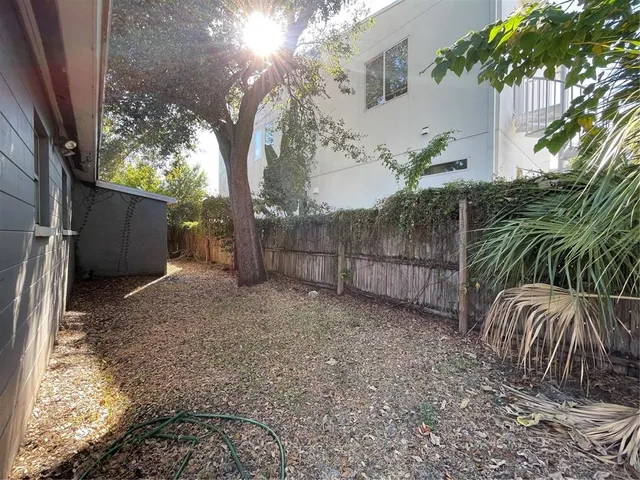 a view of backyard with wooden fence and trees
