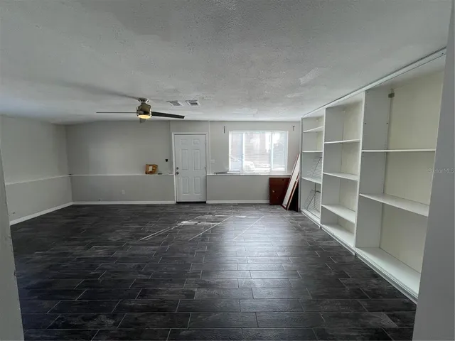 a view of an empty room with a window and wooden floor