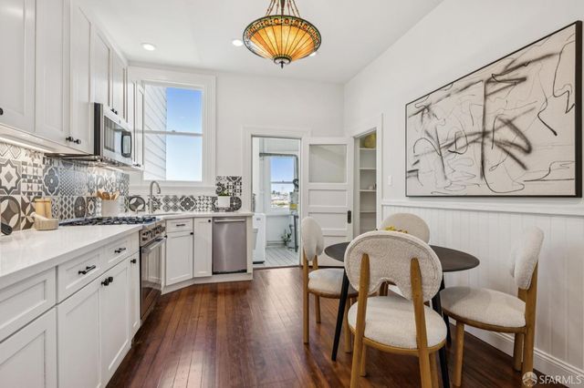 a kitchen with stainless steel appliances granite countertop a stove a sink dishwasher a dining table and chairs with wooden floor