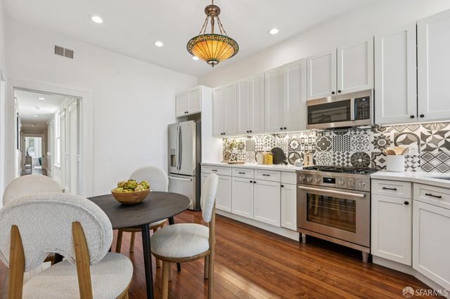 a kitchen with stainless steel appliances granite countertop a stove a sink cabinets and wooden floor