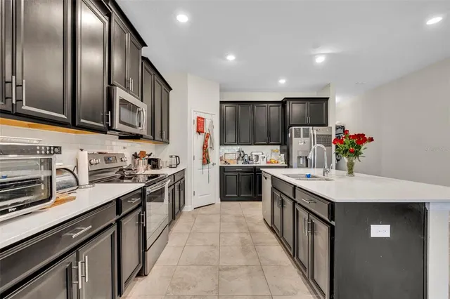 a kitchen with stainless steel appliances granite countertop a sink stove refrigerator and cabinets