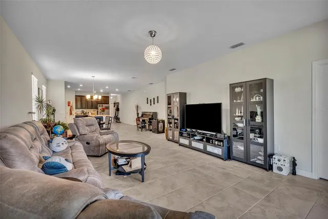 a living room with furniture a flat screen tv and kitchen view
