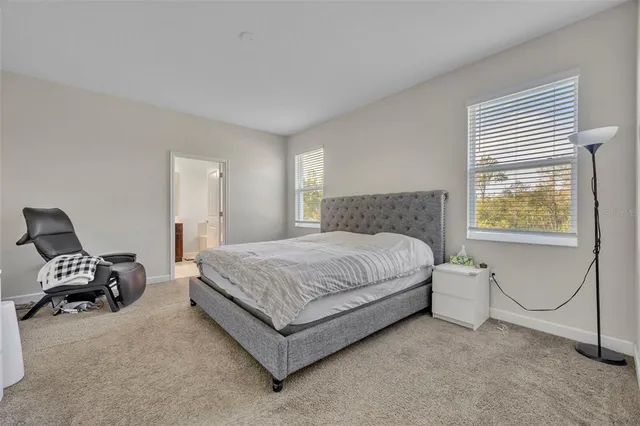 a bedroom with a bed chair and two windows