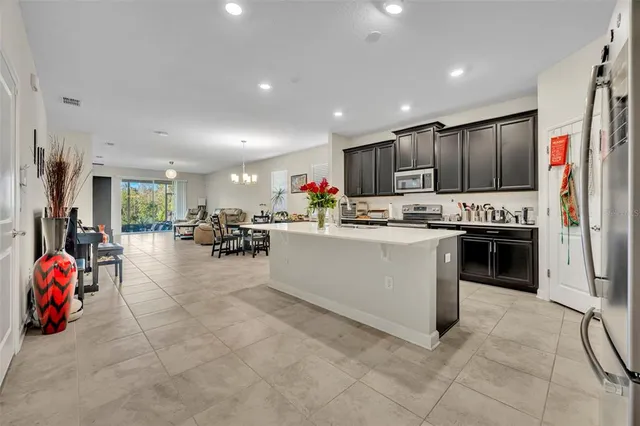 a kitchen with stainless steel appliances kitchen island granite countertop a refrigerator oven a sink dishwasher and white cabinets with wooden floor