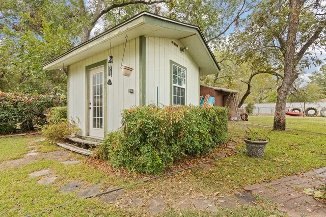 a view of a backyard with plants and a large tree
