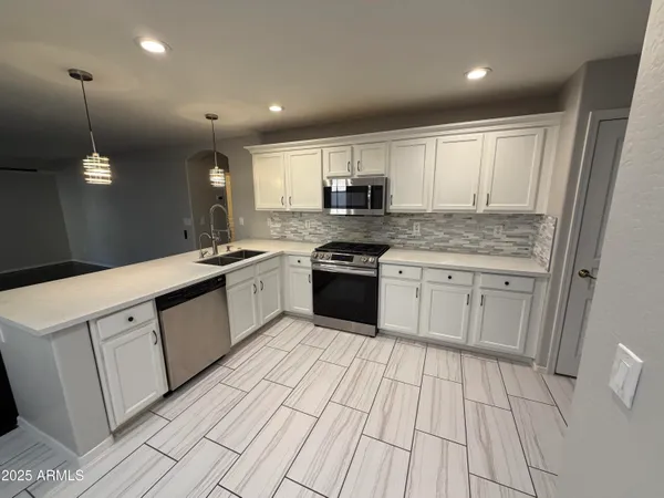 a kitchen with stainless steel appliances granite countertop a sink a stove a refrigerator and cabinets