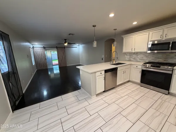 a large kitchen with stainless steel appliances granite countertop a large counter top and a stove with wooden floor