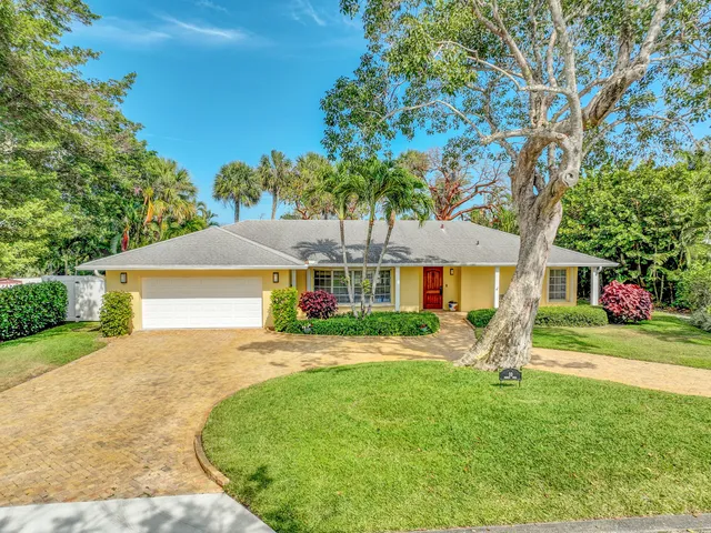 a front view of a house with a yard and potted plants
