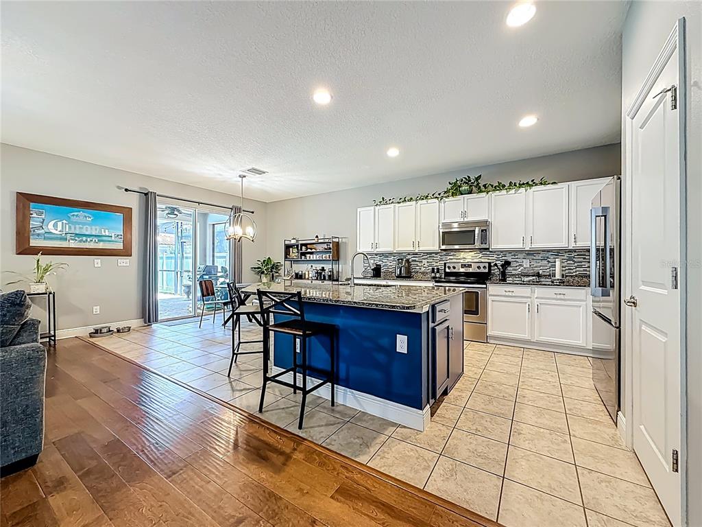 10193 Grand Oak Circle Madeira Beach, FL 33708 - Photo 14 of 67 a kitchen with stainless steel appliances granite countertop a refrigerator a stove a sink a dining table and chairs with wooden floor