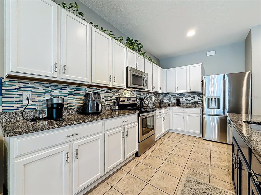 10193 Grand Oak Circle Madeira Beach, FL 33708 - Photo 19 of 67 a kitchen with granite countertop a sink stainless steel appliances and white cabinets