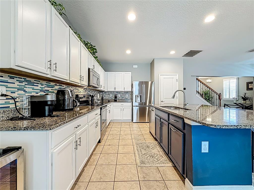 10193 Grand Oak Circle Madeira Beach, FL 33708 - Photo 21 of 67 a large kitchen with stainless steel appliances granite countertop a stove top oven a sink dishwasher a dining table and chairs