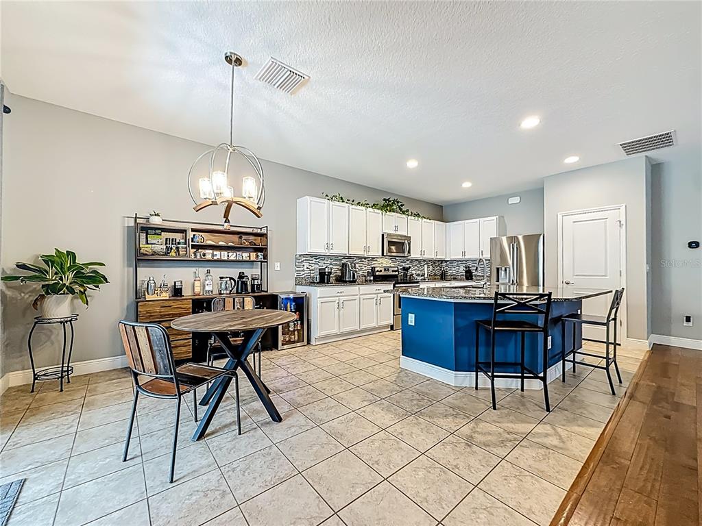 10193 Grand Oak Circle Madeira Beach, FL 33708 - Photo 24 of 67 a kitchen with stainless steel appliances kitchen island granite countertop a table chairs and a refrigerator