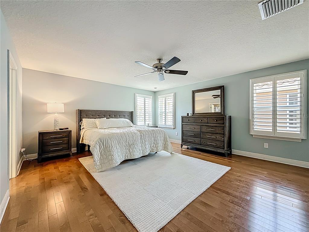 10193 Grand Oak Circle Madeira Beach, FL 33708 - Photo 27 of 67 a bedroom with a bed and dresser with wooden floor