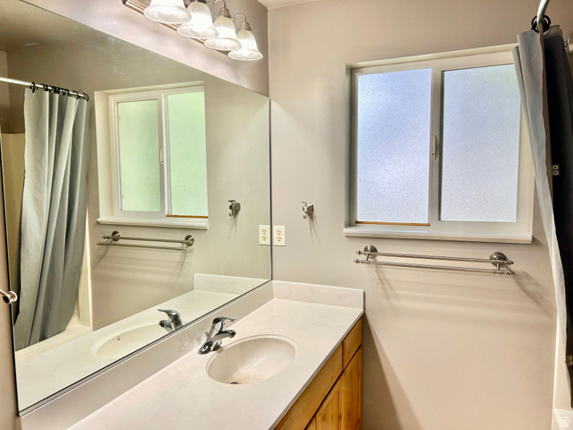 672 West 720 South Logan, UT 84321 - Photo 10 of 15 Bathroom featuring a light wood-finish vanity with a dual-basin countertop, a large wall-mounted mirror, and a frosted window