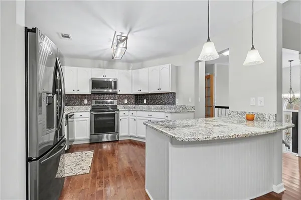 a kitchen with kitchen island granite countertop a sink cabinets a counter and stainless steel appliances