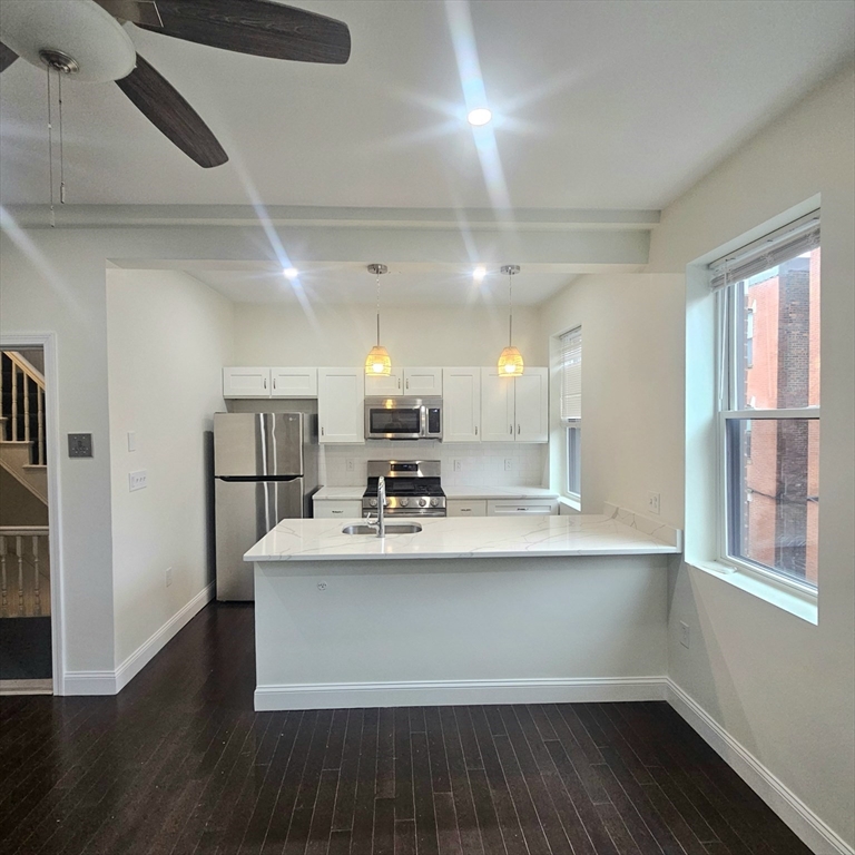 a view with kitchen island a sink wooden floor and a window