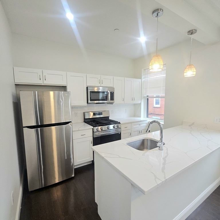 49 Charter Street, Unit 3 Boston, MA 02113 - Photo 3 of 10 a kitchen with a sink a refrigerator a microwave and cabinets