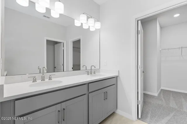 a bathroom with double vanity sinks a vanity a lamp and a mirror