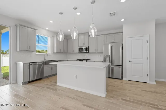 a large kitchen with a refrigerator a sink dishwasher a oven and a dining table with wooden floor