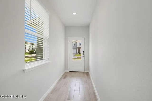 a view of a hallway with wooden floor and a window