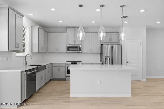 a large kitchen with stainless steel appliances granite countertop a stove a sink and a refrigerator