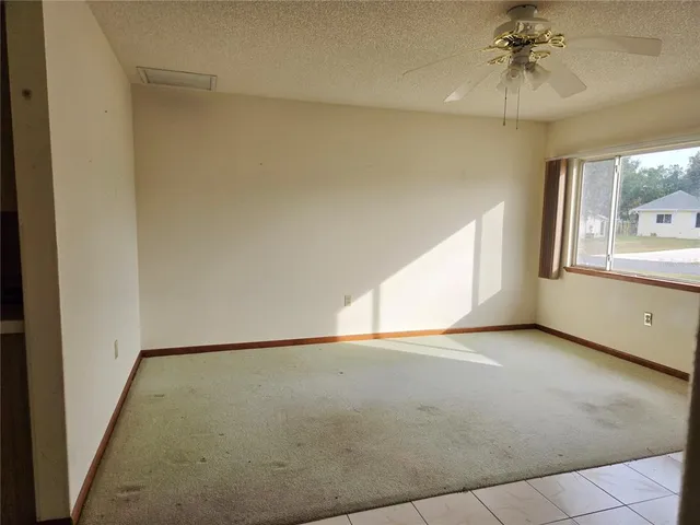 an empty room with a window and a ceiling fan