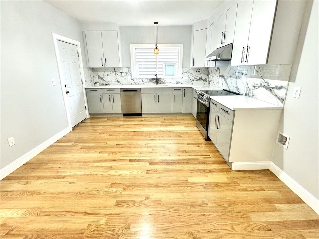 190 Hillside Street, Unit 1 Boston, MA 02120 - Photo 21 of 27 a large white kitchen with kitchen island a sink stainless steel appliances and cabinets