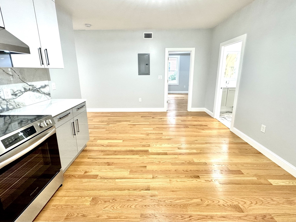 190 Hillside Street, Unit 1 Boston, MA 02120 - Photo 23 of 27 a view of a kitchen with kitchen island a sink a stove and wooden floor