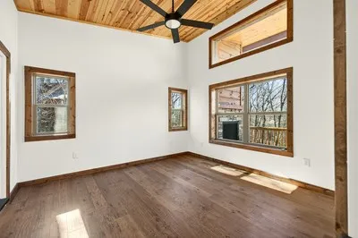 a view of an empty room with a window and wooden floor