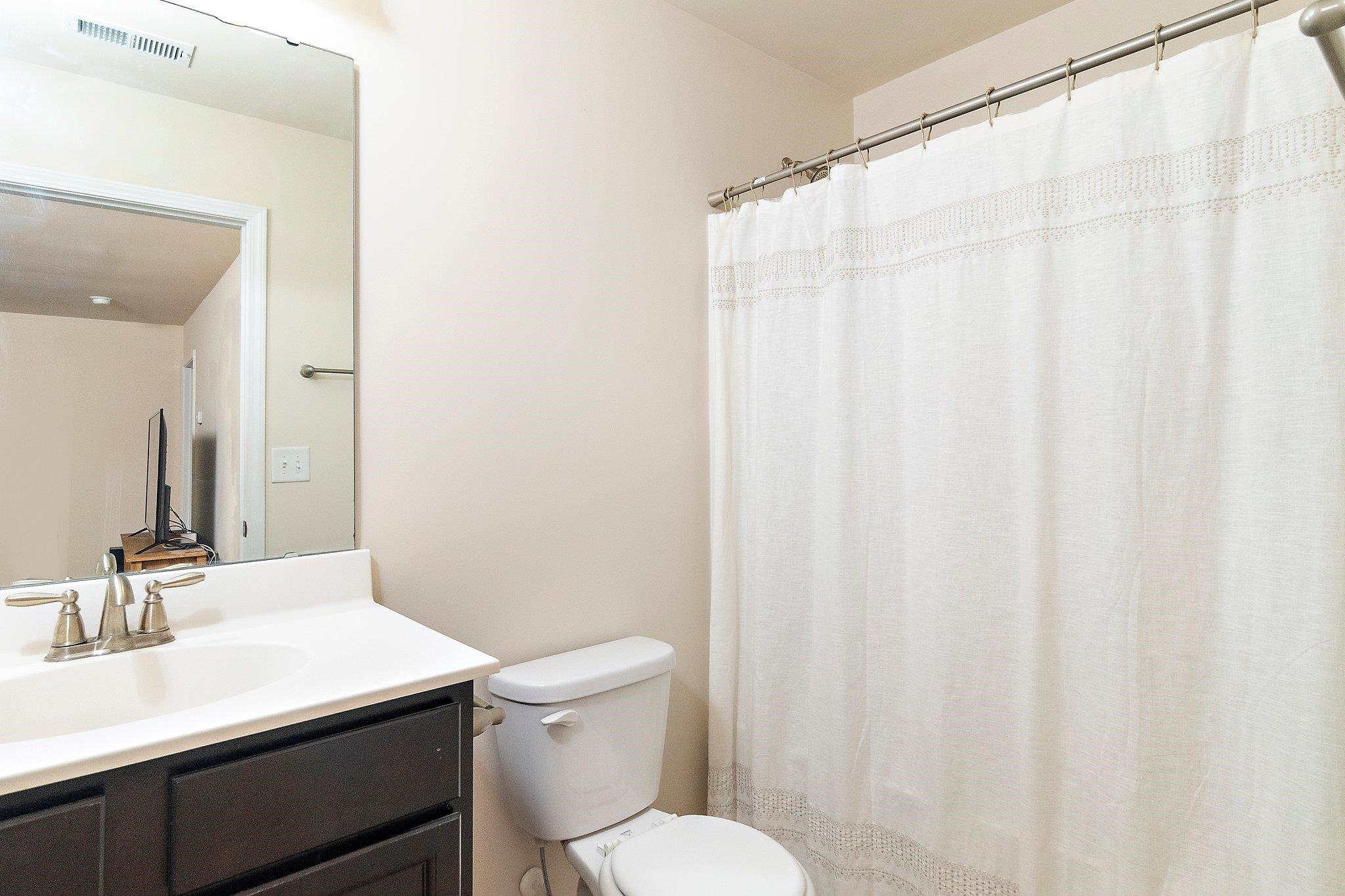 3525 Althorp Drive Raleigh, NC 27616 - Photo 24 of 28 a bathroom with a sink a toilet a mirror and shower curtain