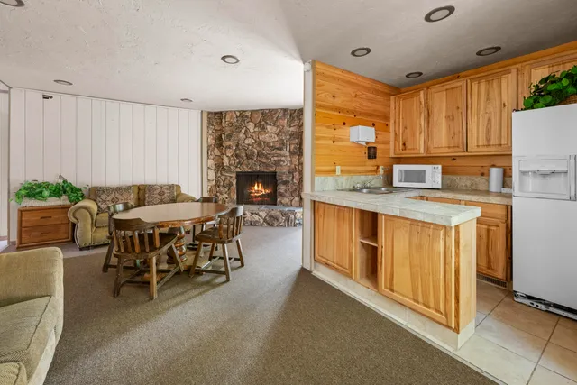 a open kitchen with stainless steel appliances granite countertop a stove a sink a refrigerator and a dining table