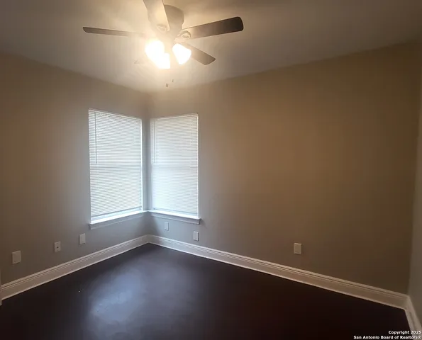 an empty room with a window and a fan