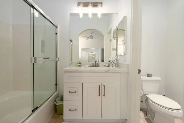 a bathroom with a granite countertop sink a toilet and a mirror