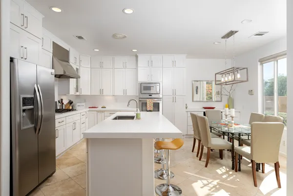 a kitchen with kitchen island a refrigerator stove and white cabinets