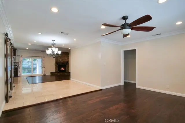 an empty room with wooden floor a ceiling fan and kitchen view