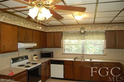 12128 Dolphin Road Bokeelia, FL 33922 - Photo 3 of 6 a kitchen with a sink a stove a microwave and cabinets