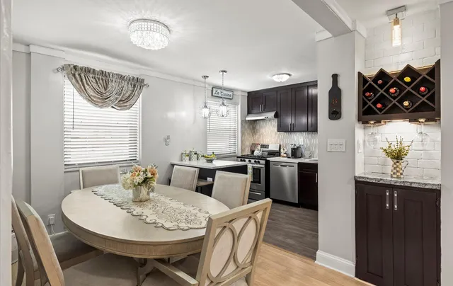 a kitchen with stainless steel appliances kitchen island granite countertop a sink a stove a dining table and chairs