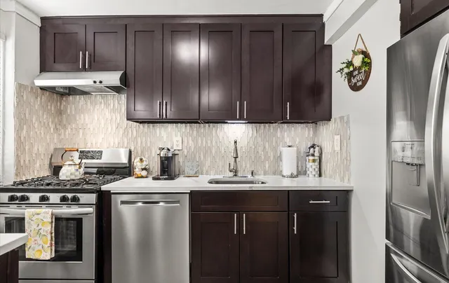 a kitchen with stainless steel appliances a sink a stove a refrigerator and cabinets