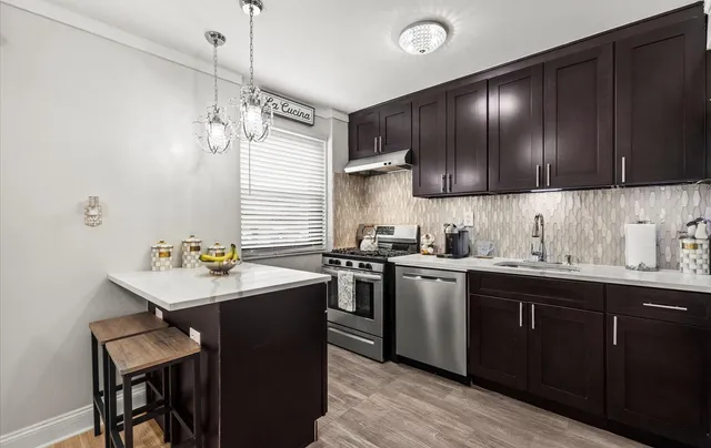 a kitchen with a sink a stove cabinets and wooden floor